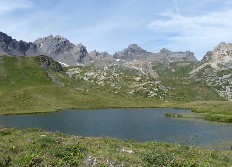 Lago alpino con acqua calma e montagne grigie sullo sfondo in Valle d'Aosta
